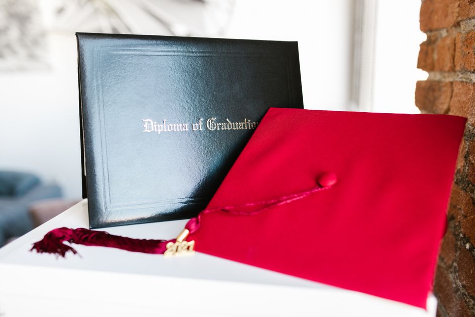 Close-up of a vibrant red graduation cap and diploma, symbolizing achievement.