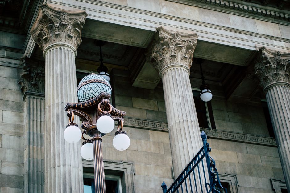 An elegant view of classic architectural columns with an antique street lamp, ideal for urban landscapes.